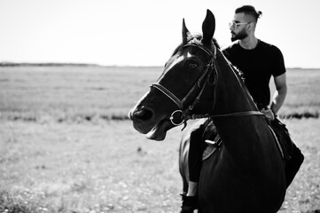 Obraz premium Arab tall beard man wear in black and sunglasses ride arabian horse.
