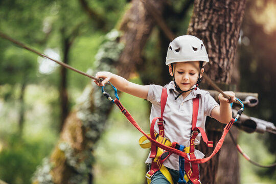 Happy child enjoying activity in a climbing adventure park on a summer day