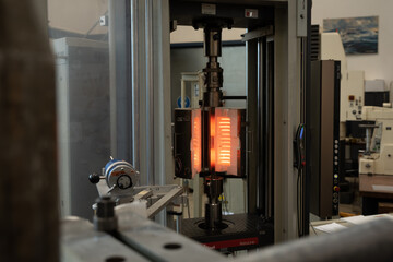 Industrielle Belastungsprüfung eines Metallstücks unter Hitze.