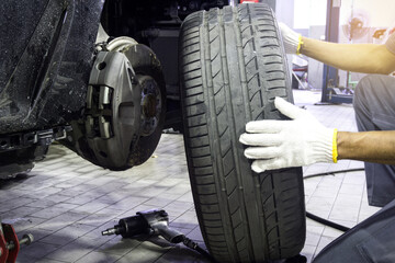 A car mechanic removes tires to check the safety of the vehicle's brake system with tool at the repair garage.