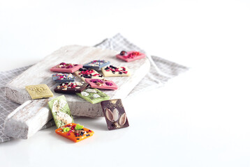 Natural Belgian chocolate of different flavors, made from organic products, matcha tea, green, blue, coconut, sprinkled with fruit chips, nuts, seeds.
