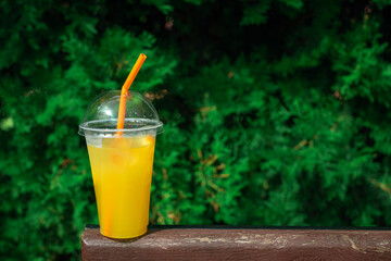 Orange lemonade in plastic glass, cooling fruit drink. Refreshing summer drinks. Plastic cup you can take with.