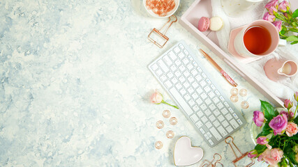 Blush pink theme cosy hygge desktop workspace with keyboard smart phone tea and rose on a stylish white marble textured background. Top view blog hero header creative flat lay. Negative copy space.