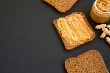 Piece of Bread with Peanut Butter on a black background, side view. Copy space.