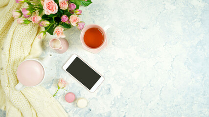 Blush pink theme cosy hygge desktop workspace with keyboard smart phone tea and rose on a stylish white marble textured background. Top view blog hero header creative flat lay. Negative copy space.
