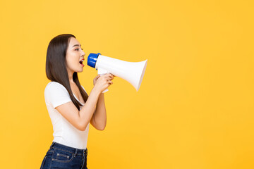 Smiling beautiful Asian woman talking on magaphone isolated on yellow background with copy space