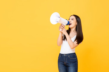 Portrait of smiling cheerful young pretty Asian woman holding megaphone making announcement in...