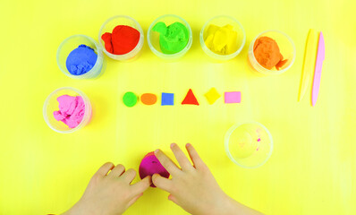 colored mass for modeling, plasticine for children's creativity, the child makes colored geometric shapes,  yellow background