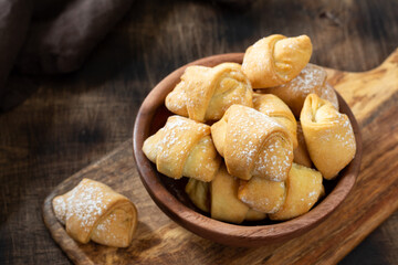 Lots of bagels. Puff pastry in a wooden plate on a brown table. Cookies close up