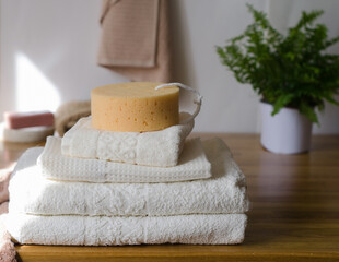 A stack of clean white cotton bath towels lie on a wooden surface in the interior.