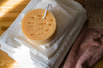 A stack of clean white cotton bath towels lie on a wooden surface.