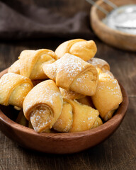 Lots of bagels. Puff pastry in a wooden plate on a brown table. Cookies close up
