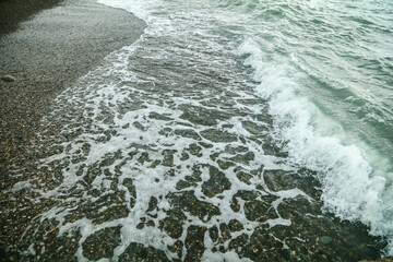 Stone pebbles on the seashore washed by a wave of water.