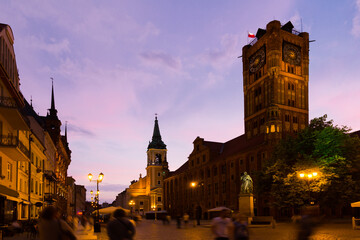 Illuminated streets of Torun with Town Hall and statue of Nicolaus Copernicus in evening