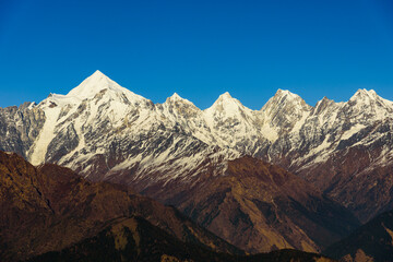 Obraz premium View of Snow cladded Panchchuli peaks falls in great Himalayan mountain range & alpine grass meadows enroute to Khalia Top trekk trail at small hamlet Munsiyari, Kumaon region, Uttarakhand, India.