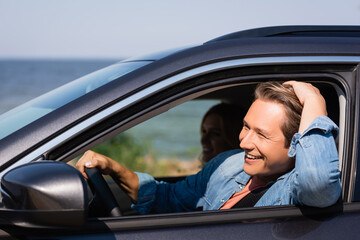 Selective focus of man driving car near wife during weekend