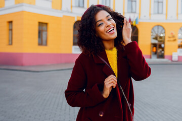 Mirthful   woman with dark skin posing outdoor. Autumn season. Wearing wool coat and cherry beret.