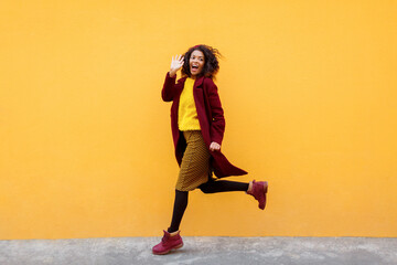 Fototapeta na wymiar Full length image of excited black woman jumping with happy face expression on yellow background.