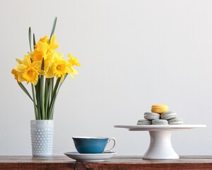 still life with cakes, daffodils, and a cup of tea