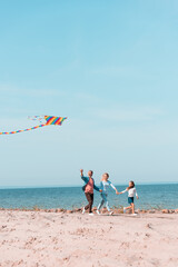 Selective focus of family running with kite on seaside