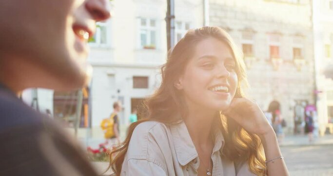 Close up portrait of cheerful beautiful young female smiling at talking with friends in good mood in city. Joyful male and females chatting and laughing outdoors. Urban style. Conversation concept