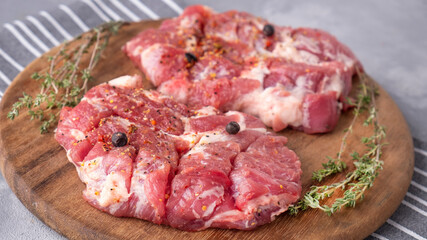 Raw chop pork neck pieces on a board with spices. Closeup