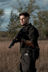 Fototapeta premium Young soldier in black uniform with an assault rifle.