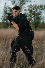 Young soldier in black uniform aiming a pistol