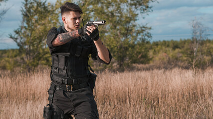Fototapeta premium Young soldier in black uniform aiming a pistol
