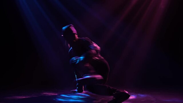 Good looking stylish man dancing street dance breakdance, hip hop isolated over smoky background in tracksuit. Close up.
