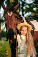 Obraz premium Friendship of a child with a horse. Treating autism with a horse. Interaction of a girl with autism and a horse. Walking a child with a horse in the fall.