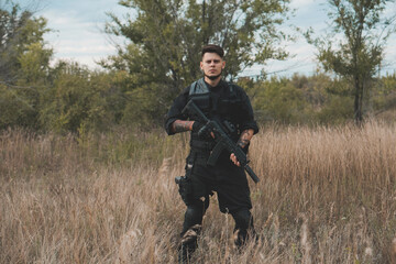 Young soldier in black uniform with an assault rifle.