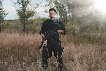 Young soldier in black uniform with an assault rifle.