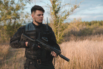 Young soldier in black uniform with an assault rifle.