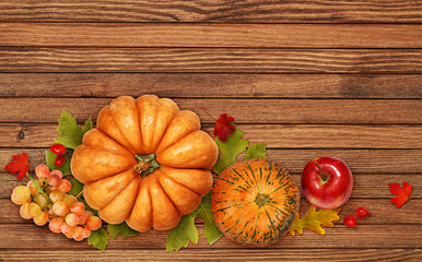 Autumn arrangement with pumpkins, grapes, apple and colorful leaves on wood