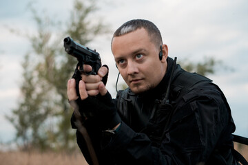 Special forces soldier in black uniform aiming a pistol.