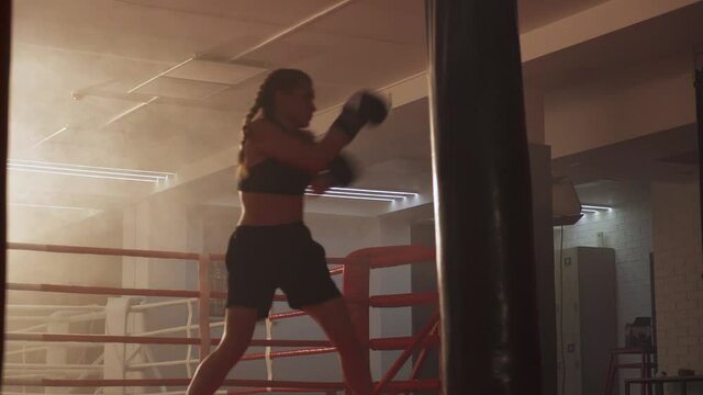 Sports motivation, kickboxing, woman fighter trains his punches, beats a punching bag, training day in the boxing gym, strength fit body.