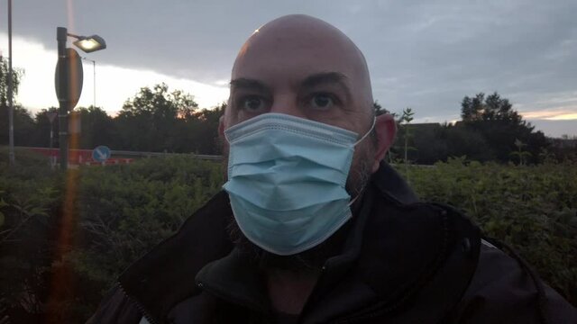 Male in workplace wearing uniform adjusts PPE face mask against corona virus at sunrise
