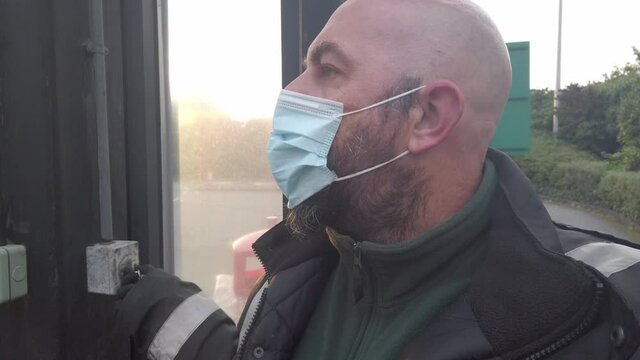 Male opening corrugated security roller shutter wearing PPE corona virus face mask