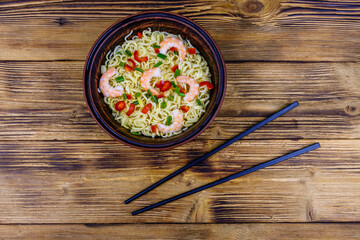 Instant noodle with shrimps, red pepper and green onion in a ceramic bowl. Japanese food. Top view