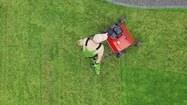 Caucasian Man With Push Aerator Puncturing Soil Of Large Green Grassy Area. Lawn Care And Maintenance Of Property Yard. 