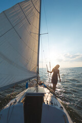A girl in a dress stands on a sailing yacht