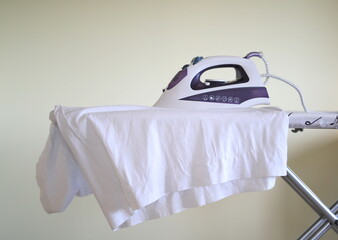 Clothes iron on ironing board with garments inside house