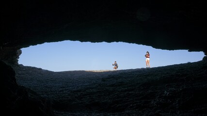 Two women take photos at the entrance of a cave