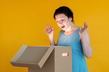 Gift surprise. Shopping bonus. Excited woman looking at opened shining box. Isolated on orange copy...