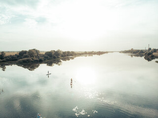 Top view of tourists on lake with SUP-boards. Beautiful clear water with people floating on boards engaged in sup-surfing. Seascape with people rowing on boards on background horizon
