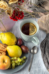 Still life with a cup of tea, a vase with a bouquet, fruits and a banana muffin.