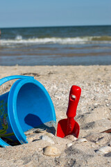 A baby bucket and a shovel lie on the seashore.