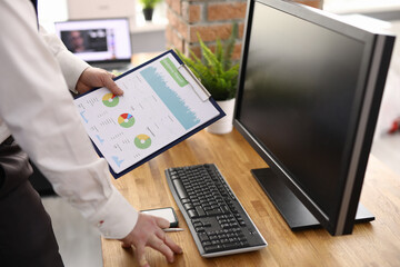 Male hand holds charts with commercial indicators in workplace. Small and medium business...