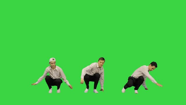 Three guys doing break dance in synch looking at camera on a Green Screen, Chroma Key.